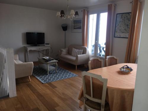 a living room with a table and chairs and a television at Baie Sud Cayeux sur Mer ciel in Cayeux-sur-Mer