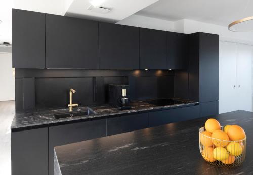 a kitchen with black cabinets and a basket of fruit at Penthouse mit Dachterrasse, Meerblick, Gasgrill, Klimaanlage, Kamin, Luxus-Design-Apartment, 2 Minuten zum Strand in Binz