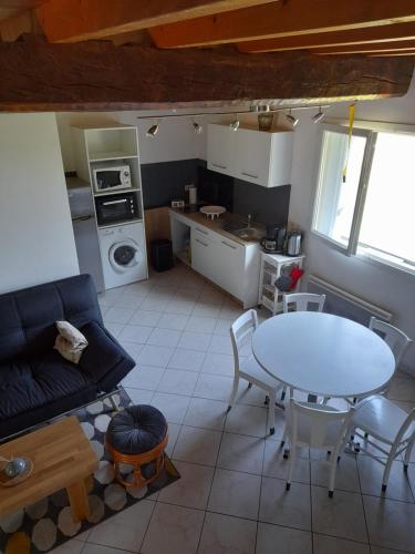 a living room with a table and a kitchen at Ô ptit gîte d'Ogenne in Ogenne-Camptort