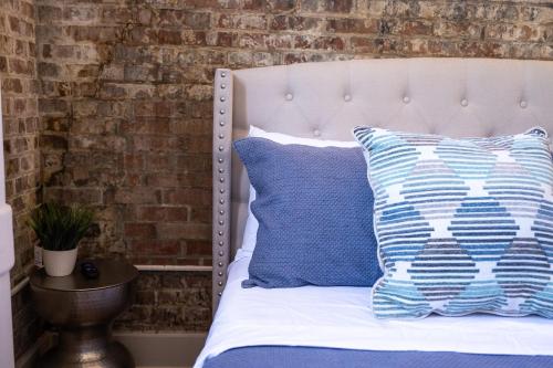 a bed with blue and white pillows and a brick wall at French Quarter Delight 8 in New Orleans
