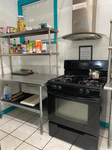 a kitchen with a stove and a shelf with food at Hoosville Hostel (Formerly The Everglades Hostel) in Florida City