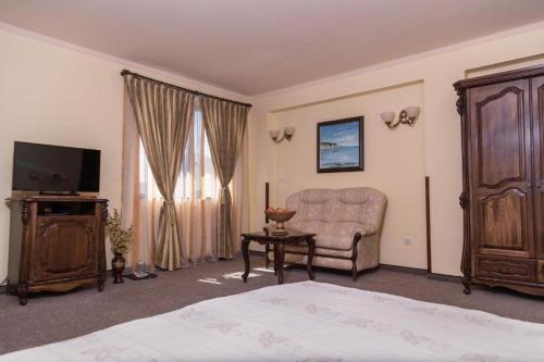 a bedroom with a bed and a couch and a television at Hotel Saint John Baptist Nessebar in Nesebar