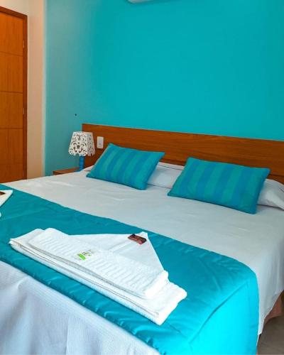 a bed with blue and white sheets and blue pillows at Pousada Cantinho da Praia in Paraty