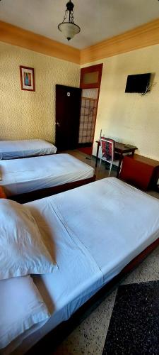 three beds in a room with a desk and a room with at Hôtel National in Al Hoceïma