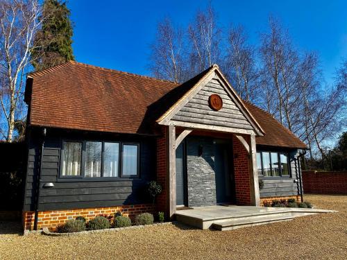 a small red brick house with a brown roof at Hillside Farm Barn in Woking