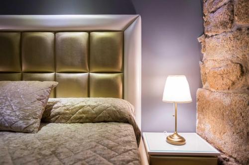 een slaapkamer met een bed met een gouden hoofdeinde en een lamp bij GuestReady - Eiffel Waterfront apartments in Porto