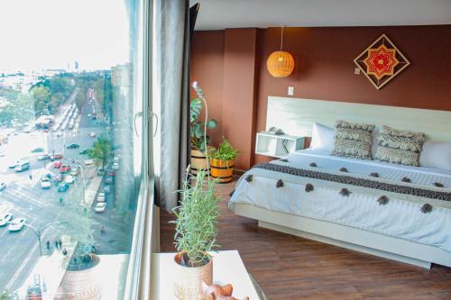 a bedroom with a bed and a large window at Hotel B Urban Xaman by Fontán Reforma in Mexico City