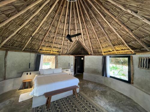 a bedroom with a bed in a straw hut at Maya Tulum By G Hotels in Tulum
