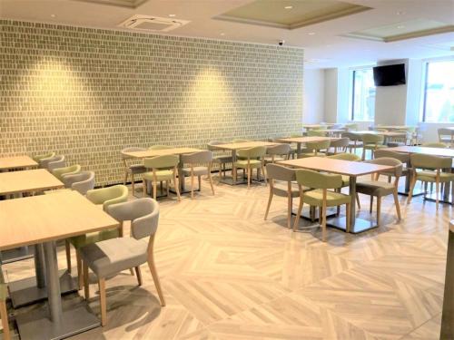 a dining room with tables and chairs and a brick wall at Smile Hotel Premium Hakodate Goryokaku in Hakodate