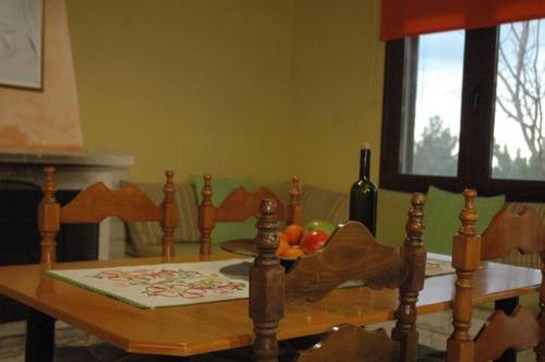 a wooden table with a bowl of fruit and a bottle of wine at Oikonomakis in Kato Zakros