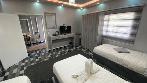 a bedroom with two beds and a desk and a television at Petra Pillars Way Hostel in Wadi Musa