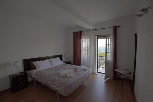 a bedroom with a bed and a door to a balcony at WATERS HOUSE - Feel at Home ir our Sea in Peniche