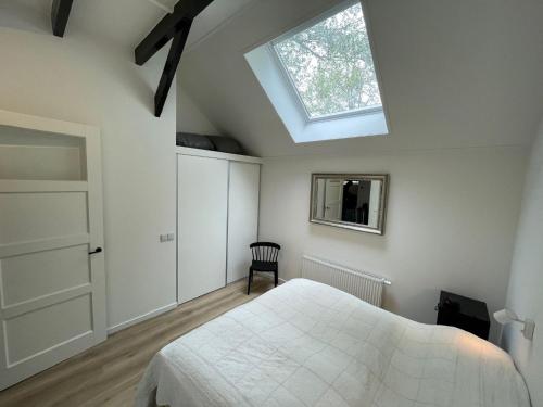 a bedroom with a white bed and a skylight at Beautiful apartment with covered terrace, in a holiday park near Rhenen in Elst