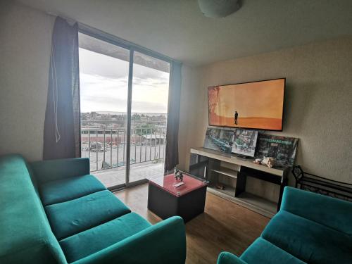 ein Wohnzimmer mit einem grünen Sofa und einem großen Fenster in der Unterkunft Departamento amoblado en condominio - 5to piso in Tacna