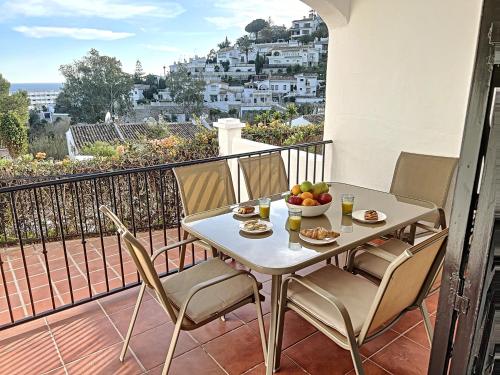 una mesa y sillas con un bol de fruta en el balcón en Agradable adosado con piscina la Hidalga, en Benalmádena