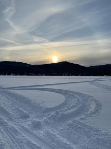 a snow covered field with the sun setting in the background at Hébergement La Belle Époque in Saint Come