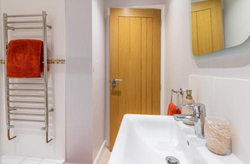 ein Badezimmer mit einem weißen Waschbecken und einer Holztür in der Unterkunft Cottage On The Quay in Wroxham