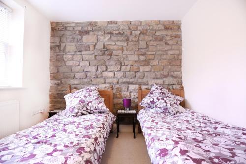 two beds in a room with a brick wall at Stable Cottage in Pateley Bridge