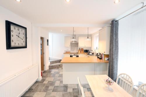 eine Küche mit einem Tisch und einer Uhr an der Wand in der Unterkunft Willow Cottage in Pateley Bridge