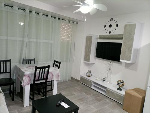 sala de estar con mesa y TV en la pared en La Cubana con Aire Acondicionado, en Santa Pola