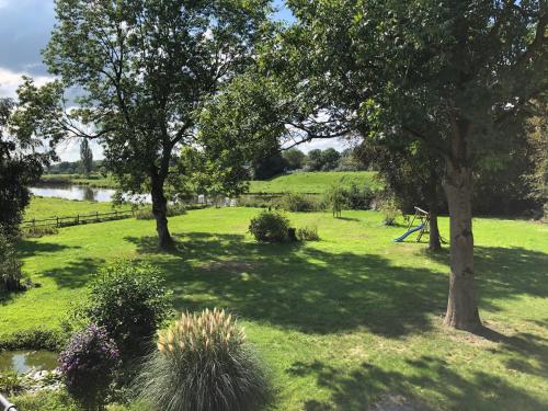 a field of grass with trees and a pond at Stedinger Landhotel & Café in Berne