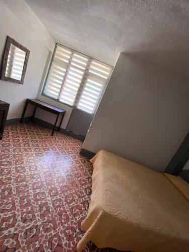 a bedroom with a bed and a desk and windows at Hotel Oseguera in Uruapan del Progreso