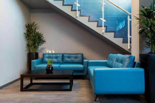 a living room with blue couches and a staircase at Radisson Blu Hotel London Stansted Airport in Stansted Mountfitchet