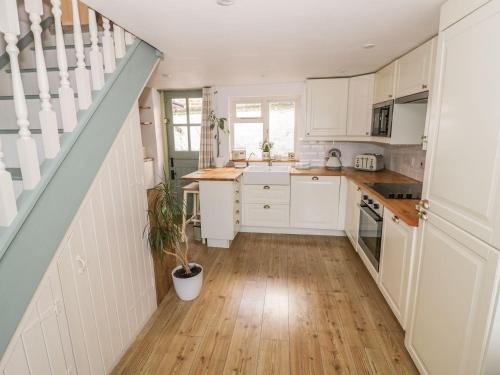 una cocina con armarios blancos y una escalera en Chapel Cottage, en Pewsey