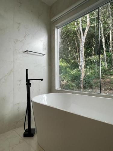 a white bath tub in a bathroom with a window at Pousada Peninsula de Buzios in Búzios