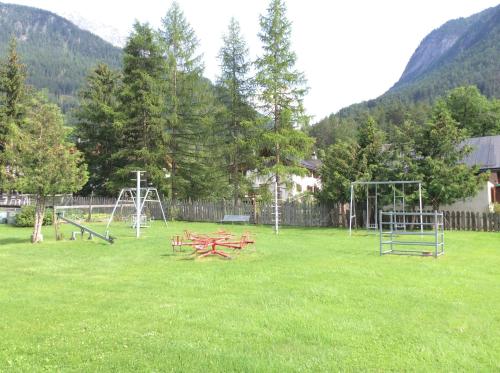 a park with picnic tables and swings in the grass at Pensiun Lischana in Sent