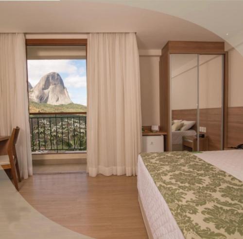 a bedroom with a bed and a view of a mountain at Cond Vista Azul Hotel in Pedra Azul