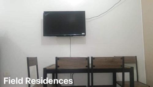 uma televisão de ecrã plano pendurada numa parede por cima de uma mesa em Field Residences em Manila
