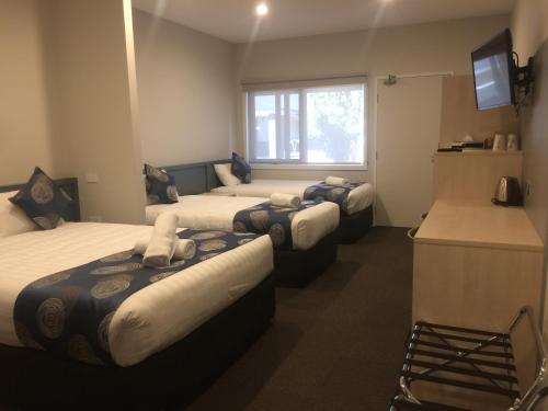 a hotel room with three beds and a window at Leumeah Lodge in Canberra