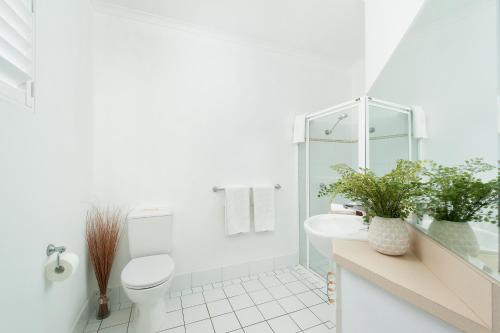 a white bathroom with a toilet and a sink at Zenith 10 in Shoal Bay
