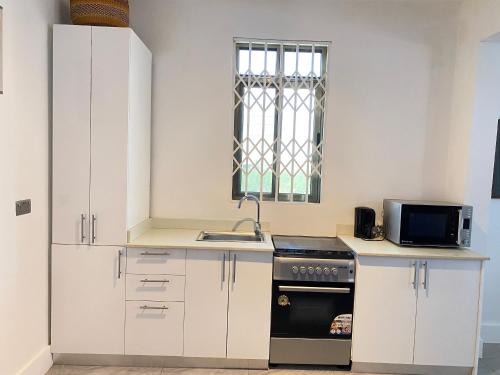a kitchen with white cabinets and a sink and a stove at Legacy Court in Ashalebotwe