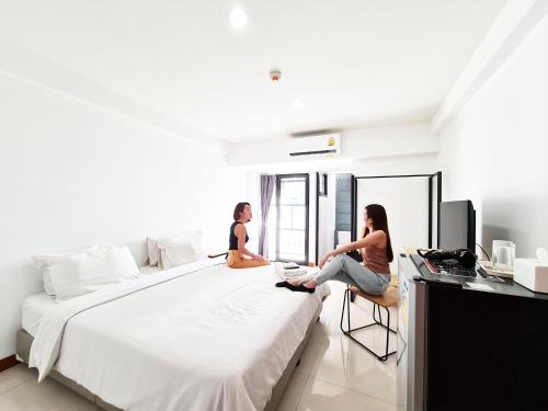 Dos mujeres sentadas en una cama en un dormitorio en Don Muang Hotel, en Bangkok