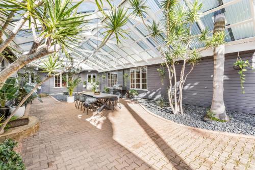 un patio con mesa, sillas y palmeras en Yallingup Lodge Spa Retreat, en Yallingup