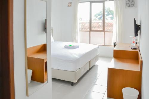 um quarto de hospital com uma cama e um espelho em Bumi Ciboled Mitra RedDoorz near Gerbang Tol Pamulihan em Jatinangor