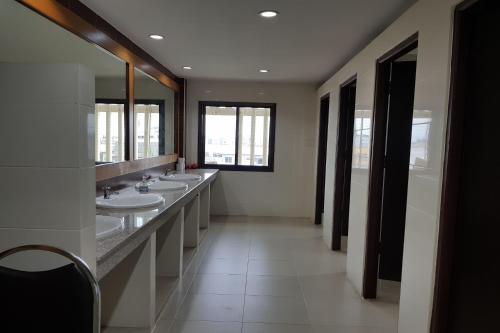 Baño con una fila de lavabos y espejos en Poonsook Phitsanulok Hotel SHA Plus, en Phitsanulok