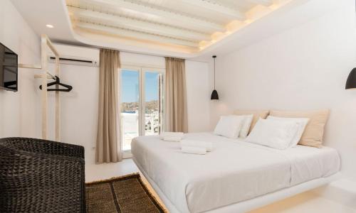a white bedroom with a large bed and a window at Luxury Ocean View Villa Mykonos Centre in Mikonos