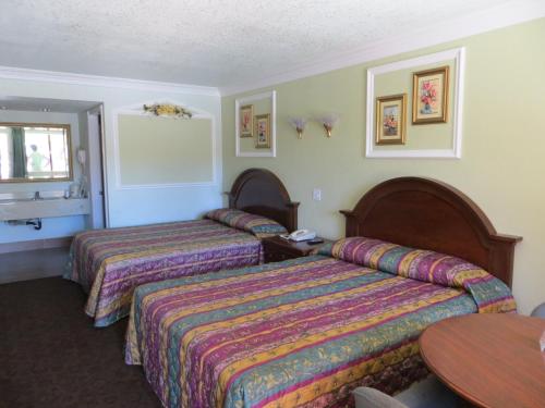 een hotelkamer met 2 bedden en een tafel bij Azusa Inn in La Puente
