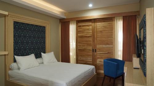 a bedroom with a bed and a blue chair at Aldeoz Residence Kuta in Kuta