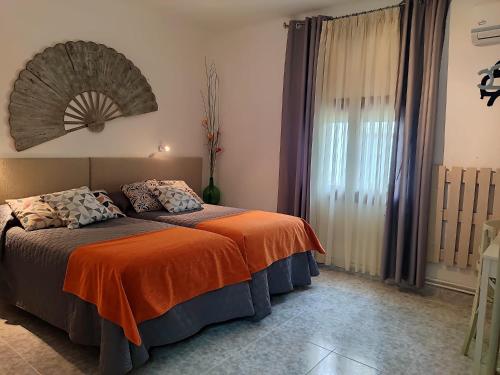 - une chambre avec un lit et une couverture orange dans l'établissement Acogedor Alojamiento, à Membrilla