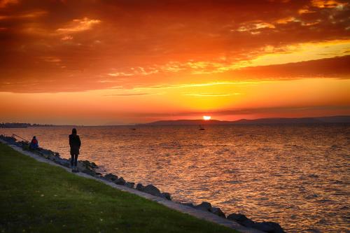 a person standing on the beach at sunset at Galerius Golden Beach Apartment in Siófok