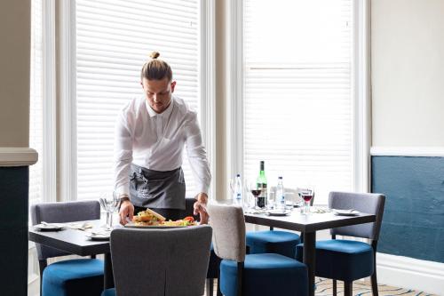 a man preparing a plate of food on a table at The Marine Hotel in Llandudno