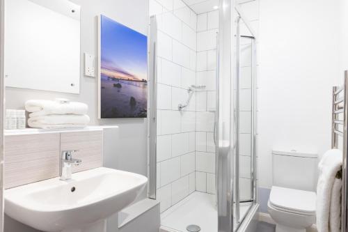 a white bathroom with a sink and a shower at The Marine Hotel in Llandudno