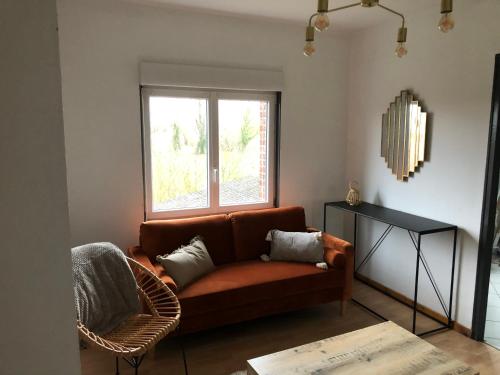 ein Wohnzimmer mit einem braunen Sofa und einem Fenster in der Unterkunft LA VILLA DEKO - Appart2 - Université et Hôpital in Beuvry