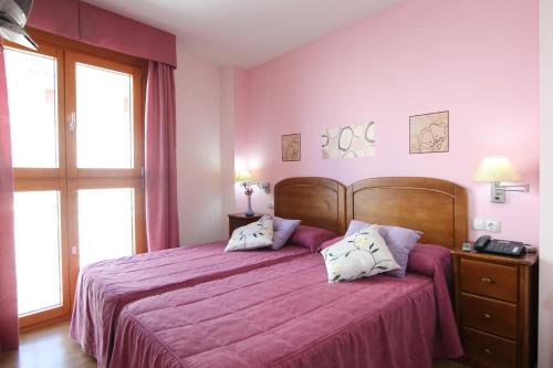 Un dormitorio con una cama grande con sábanas y almohadas púrpuras. en Hostal Campo Real Bed&Breakfast en Campo Real