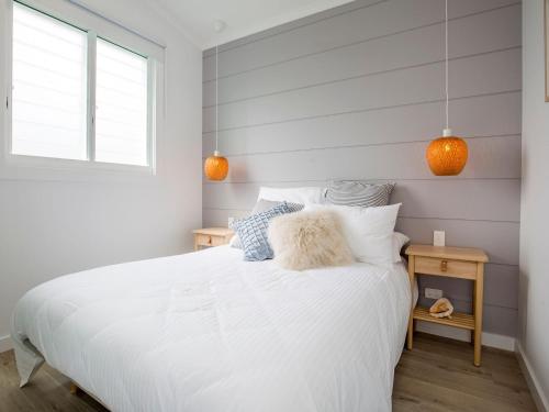 a bedroom with a white bed and a window at Unwind Pet Friendly 1 Min Walk to Beach in Culburra Beach