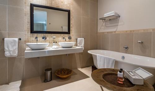 a bathroom with two sinks and a tub and a mirror at Sea Five Boutique Hotel in Cape Town